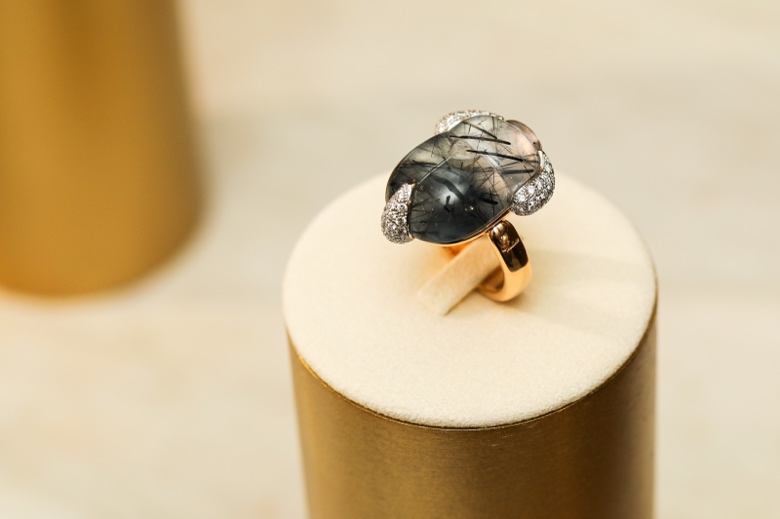 A gold ring with a black stone and diamonds on a gold cylinder

Description automatically generated
