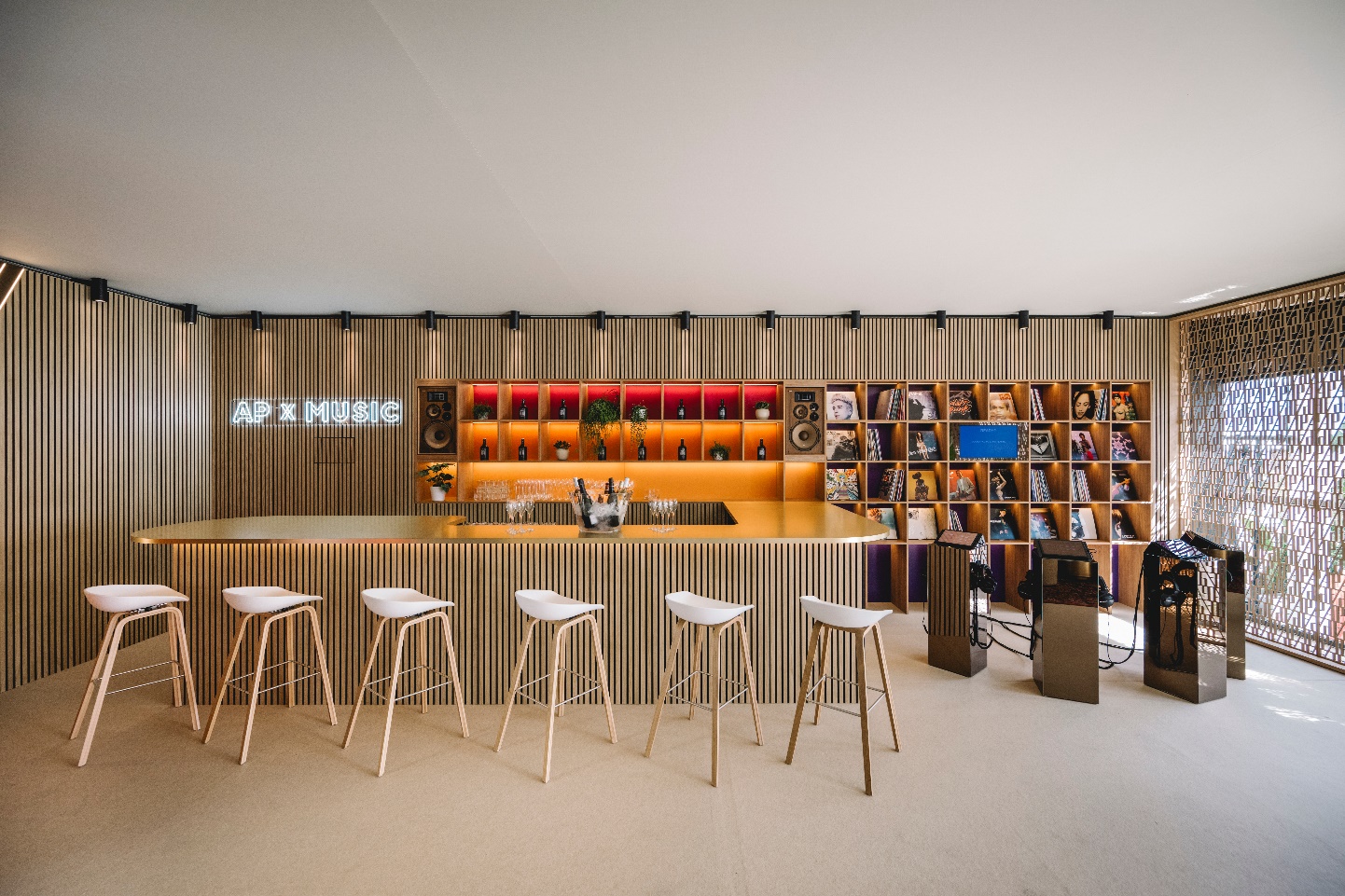 A bar with stools in front of a shelf Description automatically generated