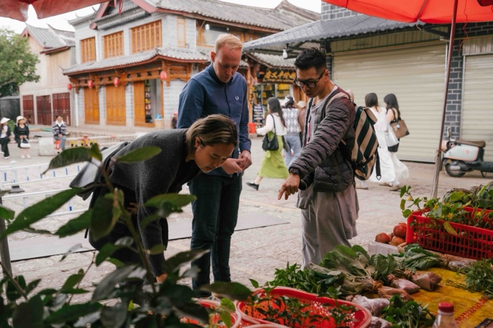 A group of people standing in a market Description automatically generated