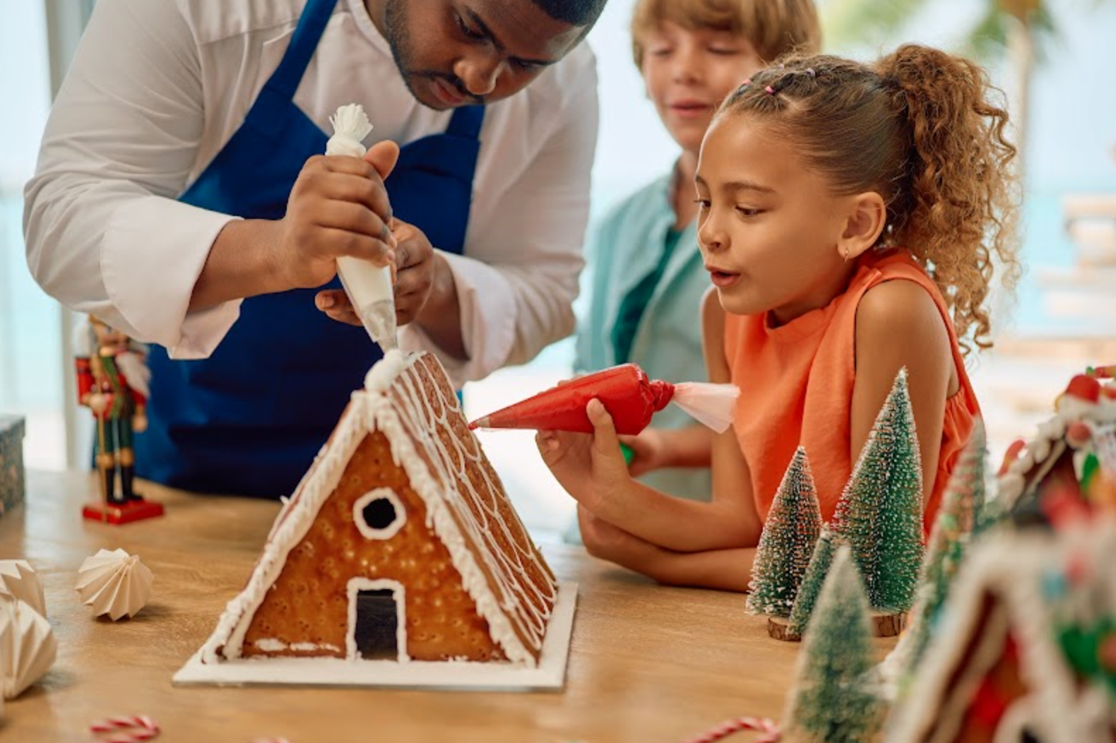 A person and a child decorating a gingerbread house

Description automatically generated