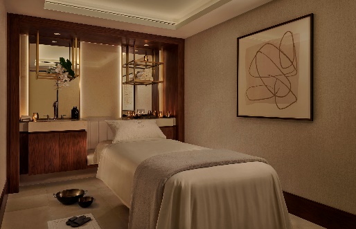 A massage room with a bed and a painting on the wall

Description automatically generated