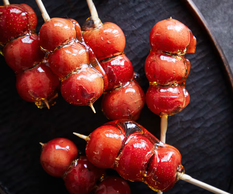 A group of red food on sticks Description automatically generated