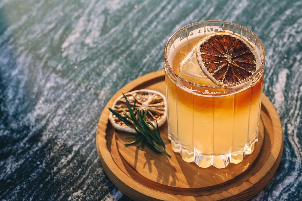 A glass of drink with a slice of orange on a wooden tray

AI-generated content may be incorrect.