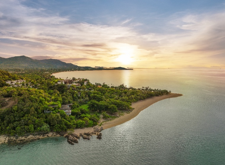 A aerial view of a beach with trees and a body of water

Description automatically generated