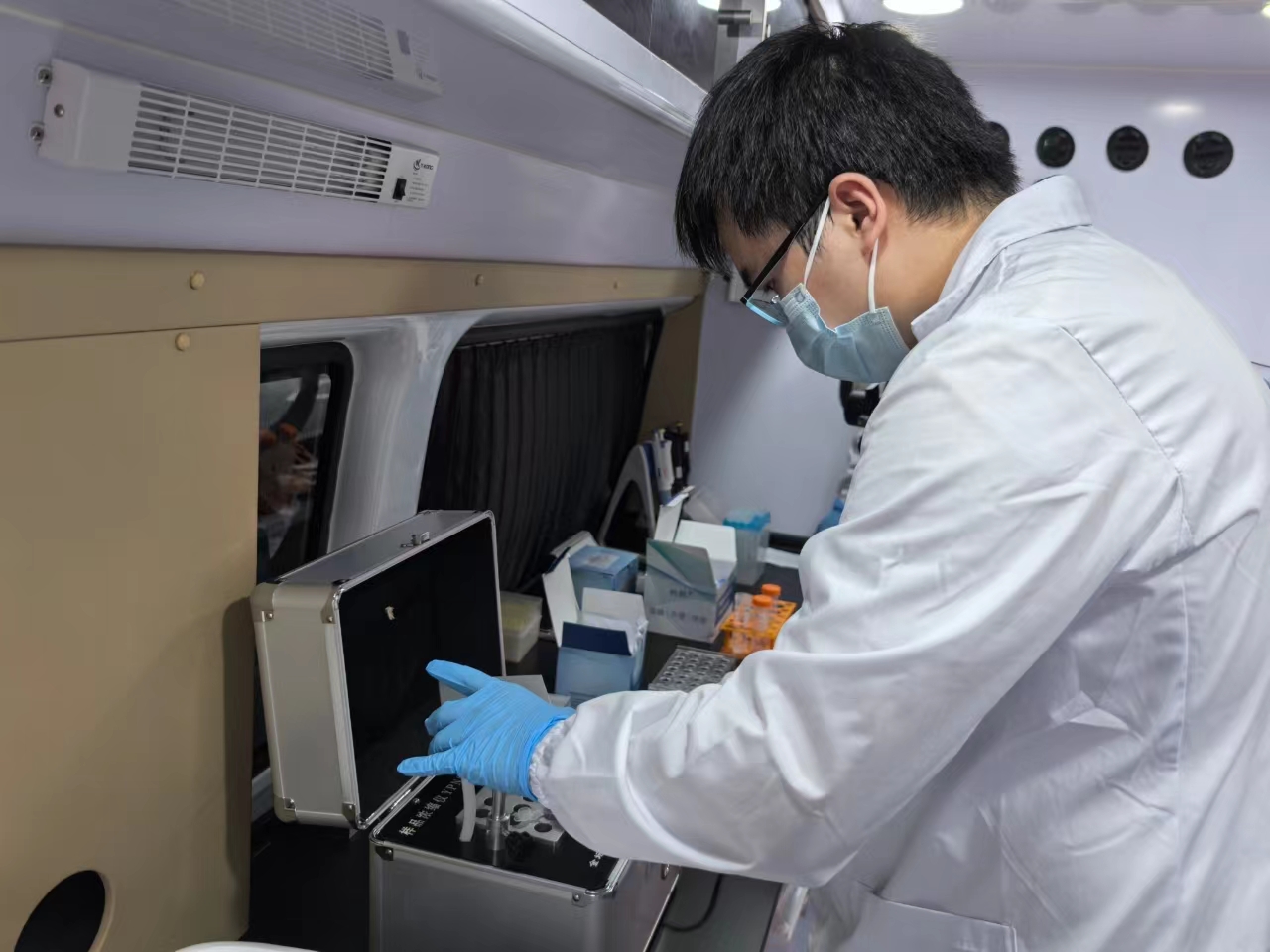 A person wearing a mask and gloves looking at a case AI-generated content may be incorrect.